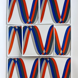 May include: A set of seven white square tiles with a repeating abstract design. Each tile features three curved bands in orange, gray, and blue, creating a wave-like pattern. The tiles are arranged in a grid.