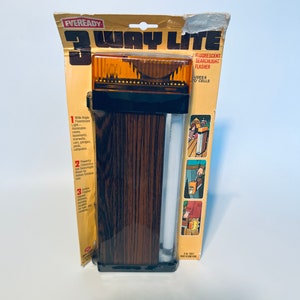 May include: A package for a 3-Way Lite fluorescent searchlight flasher by Eveready. The package shows a wood-grain design and a close-up of the flashlight. The flashlight uses 6 D cells.