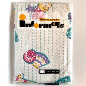 May include: A white vinyl tablecloth with a seashell pattern in pink, purple, yellow, and blue. The tablecloth is 52 inches by 70 inches and is oblong. The tablecloth is packaged in plastic and has a label that says "Informals Vinyl Flannel-backed Tablecloth".