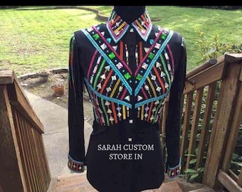 Pode incluir: Camisa preta de manga comprida com enfeites geométricos coloridos. A camisa apresenta gola, franjas decorativas e o texto "SARAH CUSTOM STORE IN". O design incorpora detalhes turquesa, laranja, verde e rosa.