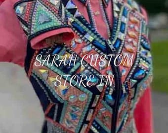 Pode incluir: Casaco de exposição equestre rosa com intrincados trabalhos de contas e enfeites de joias. O casaco tem fecho de correr, mangas compridas e gola. O texto "SARAH CUSTOM STORE IN" é visível no casaco.
