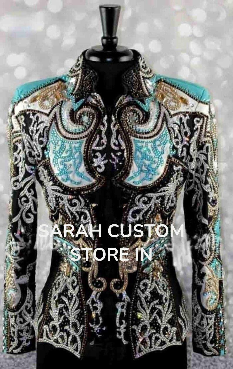 May include: A black jacket with intricate silver, gold, and turquoise embellishments. The jacket features ornate patterns, sparkling details, and the text "SARAH CUSTOM STORE IN". This garment is likely for equestrian or show apparel.