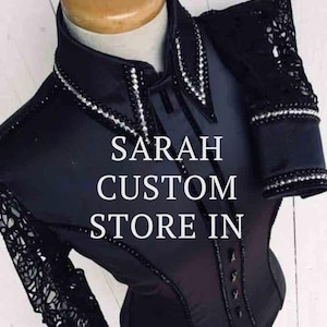 Könnte beinhalten: Schwarzes Reitshirt mit Spitzenärmeln und -kragen, verziert mit Strasssteinen. Das Shirt trägt den Text "SARAH CUSTOM STORE IN". Das Design umfasst eine Knopfleiste und eine taillierte Passform.