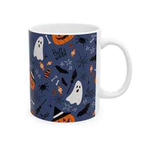 Peut inclure: Un mug en céramique blanche avec un fond bleu foncé orné d'un motif répétitif de citrouilles orange, fantômes blancs, chauves-souris noires, araignées, toiles, étoiles, os, balais et bonbons, avec le texte Halloween et Boo.