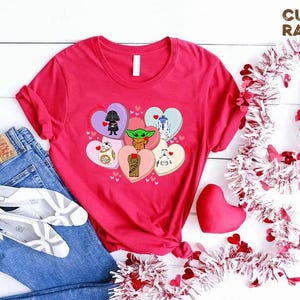 May include: A red t-shirt featuring Star Wars characters on heart-shaped designs. The shirt is paired with blue jeans, white shoes, and decorative hearts. The text "CUSTOM RANDOM GIFTS" is visible.
