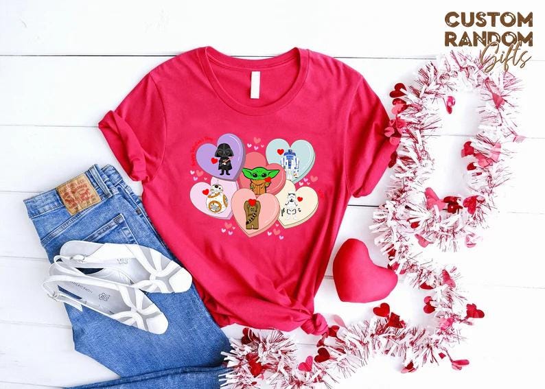 May include: A red t-shirt featuring Star Wars characters on heart-shaped designs. The shirt is paired with blue jeans, white shoes, and decorative hearts. The text "CUSTOM RANDOM GIFTS" is visible.
