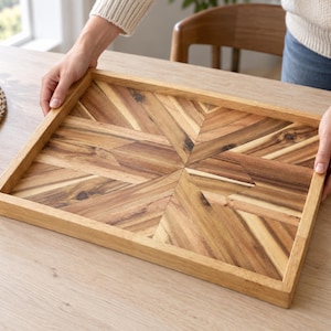 May include: A rectangular wooden serving tray featuring a geometric starburst pattern created from inlaid wood pieces with varying natural brown grain tones and a smooth finish, framed by a solid wood border with raised edges.