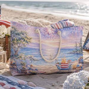 Könnte beinhalten: Eine große Strandtasche mit einer Illustration einer Strandszene mit Feuerwerk, Stühlen und einem Picknickkorb. Die Tasche hat Seilgriffe und ist mit einer weißen Decke und einem rot-weiß-blau gestreiften Handtuch gefüllt. Im Hintergrund ist eine amerikanische Flagge zu sehen.