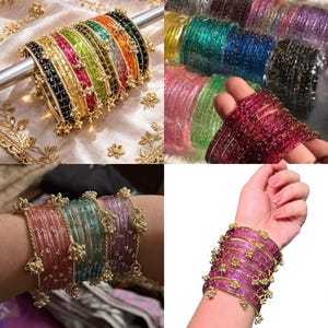 Può includere: Una collezione di braccialetti colorati in varie tonalità, tra cui rosa, verde e oro. Alcuni braccialetti hanno accenti dorati e piccoli ciondoli pendenti. I braccialetti sono esposti su un'asta d'argento e sui polsi.