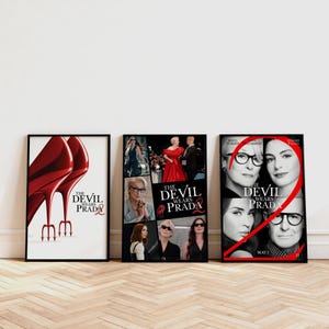 May include: Three framed posters for the film "The Devil Wears Prada". The posters feature images of the film's stars and iconic imagery, including red high heels and the film's title. The posters are displayed on a light wood floor.