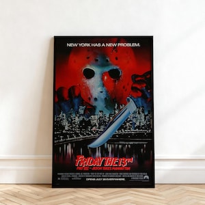 May include: A framed film poster for Friday the 13th Part VIII: Jason Takes Manhattan. The artwork features a large red hockey mask over a dark New York City skyline, with a hand holding a silver knife. Text reads: New York has a new problem.