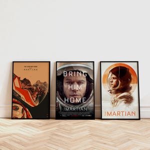 May include: Three framed movie posters for "The Martian" film. The posters feature images of astronauts in space suits, with text including "Bring Him Home" and "The Long Way Home - Martian". The posters are in black frames.