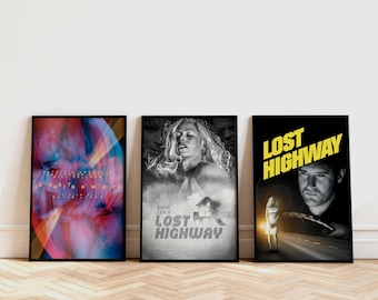 May include: Three framed movie posters for "Lost Highway" are displayed against a white wall. The posters feature different artistic designs, including abstract art, a black and white portrait, and a man on a road.