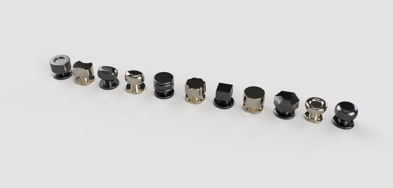 May include: A selection of ten cabinet knobs in diverse shapes and finishes. The knobs feature designs such as cylindrical, faceted, and spherical, with colours including silver, gold, and black.