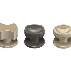 May include: Five cabinet knobs in different designs and colours are displayed. The knobs include a dark grey cylindrical knob, a tan, curved knob, a dark grey rounded knob, a tan, rounded knob, and a dark grey, stacked knob.