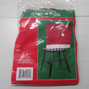 Puede incluir: Una funda de silla roja en un paquete de plástico, diseñada para parecerse a un gorro de Papá Noel. El paquete dice "Chair Cover" y "Housse de Chaise". La funda se muestra en una silla negra con un ribete blanco.