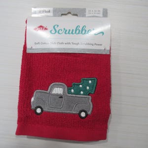 Op de afbeelding: Een rode vaatdoek met een grijze vrachtwagen met een groene kerstboomapplicatie. De doek meet 30 x 30 cm en heeft het woord "Scrubbe" op de verpakking staan.