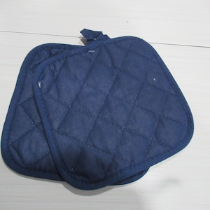 Puede incluir: Dos agarraderas acolchadas de color azul marino con un patrón de diamantes. Cada agarradera tiene un lazo para colgar. Las agarraderas están diseñadas para proteger las manos del calor al manipular utensilios de cocina calientes.