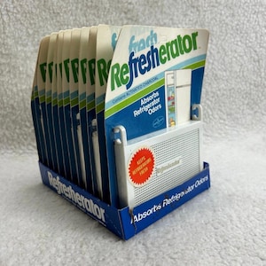 May include: A display of "Refresherator" refrigerator odor absorbers. The packaging is white, blue, and green, with the words "Absorbs Refrigerator Odors." The display box is blue with the product name printed on it. The product contains activated charcoal.