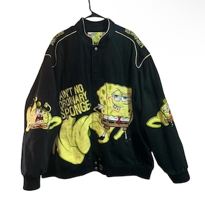 Pode incluir: Casaco bomber preto com gráficos do Bob Esponja. O casaco tem detalhes bordados em amarelo e as frases "SpongeBob SquarePants" e "Ain't No Ordinary Sponge". A frente e as mangas exibem ilustrações do Bob Esponja.