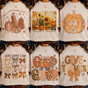 May include: A collection of six beige crewneck sweatshirts featuring various autumn-themed graphic prints including pumpkins, sunflowers, bows, and text such as take me to the pumpkin patch, Pumpkin Season, God says I am, God is so good, and Give Thanks.