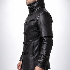 May include: Black leather jacket with a high collar and multiple buckle closures. The jacket features a unique design with short sleeves and a tailored fit. A stylish outerwear piece.