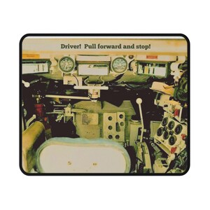 Puede incluir: Alfombrilla de ratón con el interior de un vehículo militar. La imagen muestra indicadores, palancas y el texto "Driver! Pull forward and stop!" en un estilo vintage.