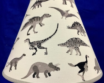 May include: A white lampshade with a dinosaur pattern. The dinosaurs are in shades of gray and black on a white background.