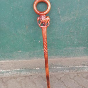 May include: A wooden walking stick with a carved elephant figure and a circular handle. The stick is a rich brown color with a spiral design carved into the shaft. The elephant is intricately detailed.