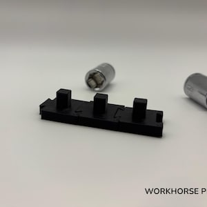 May include: A black plastic tool with three raised square posts is centered in the image. Two silver metal sockets are on either side. The text "WORKHORSE PRINTS" is at the bottom.