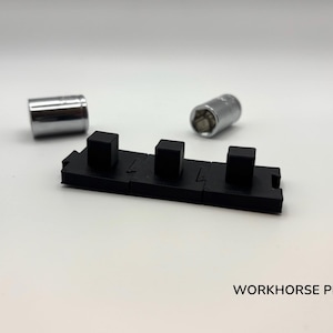 May include: A black plastic component with three raised square sections, and two silver metal sockets. The text "WORKHORSE PRINTS" is visible in the lower right corner. The items are on a white background.