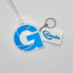 May include: A blue and white keychain with the word "Granite" printed on a white tag. The keychain also features a large blue and white "G" logo with a clear plastic strap.