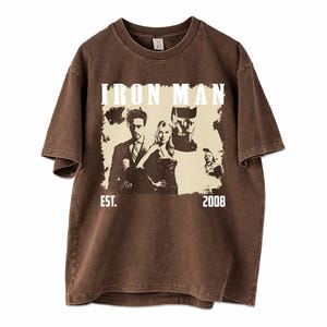 May include: Brown t-shirt with an Iron Man graphic, the words "IRON MAN" above the image, and "EST. 2008" below. The shirt has a vintage, distressed appearance.