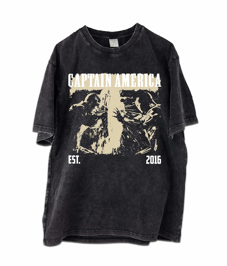 May include: Black t-shirt with a distressed graphic featuring the text "CAPTAIN AMERICA" above a beige image of two figures in action. The text "EST. 2016" is below the image. The shirt has a vintage, worn look.