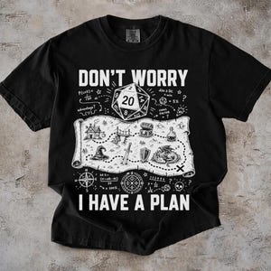 May include: A black t-shirt featuring a white graphic print with the text DON'T WORRY I HAVE A PLAN. The design includes a 20-sided die, a fantasy map with a dragon, sword, shield, treasure chest, and various mathematical gaming notations.