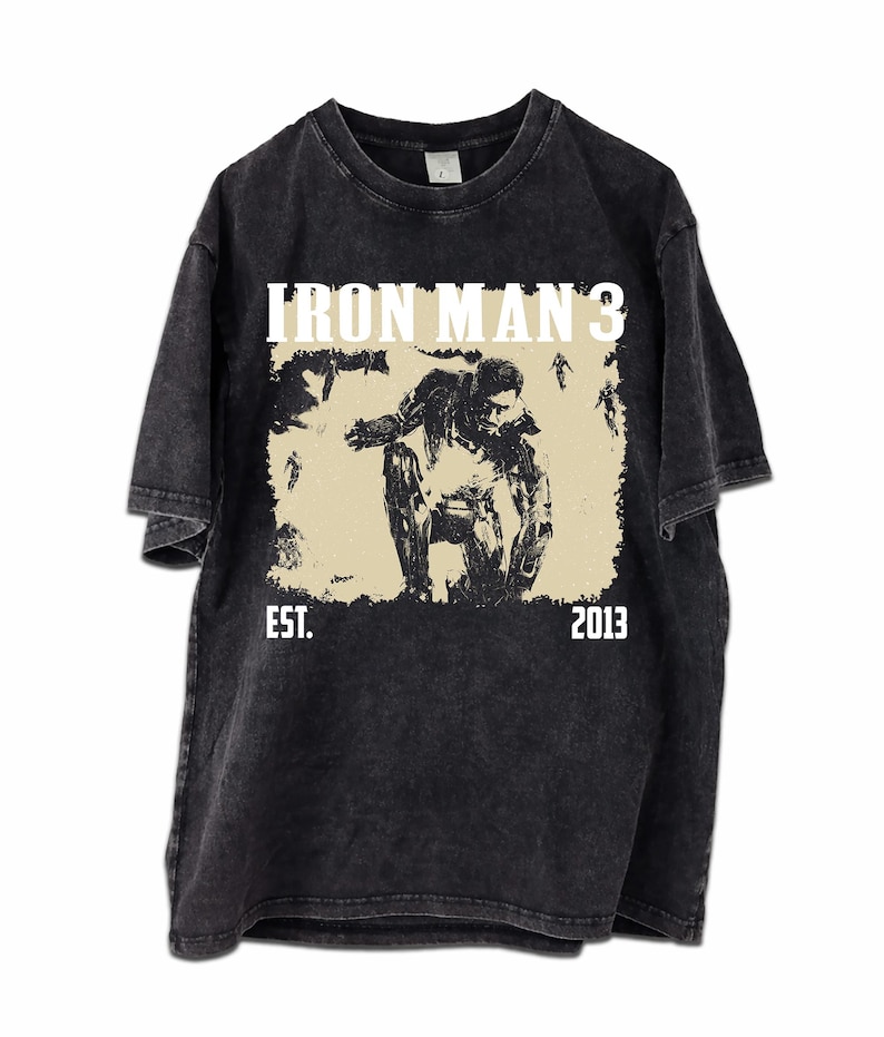 May include: Dark grey t-shirt with a distressed graphic of Iron Man from Iron Man 3. The design includes the text "IRON MAN 3" above the image and "EST. 2013" below. The shirt has a vintage, worn appearance.