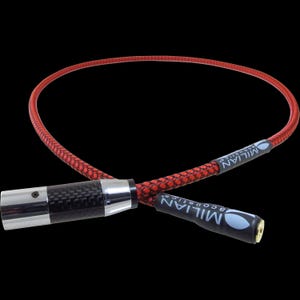 Może przedstawiać: Czerwono-czarny pleciony kabel audio ze srebrnymi i karbonowymi złączami. Na kablu znajduje się napis "MILIAN ACOUSTICS" wydrukowany na czarnym pasku.
