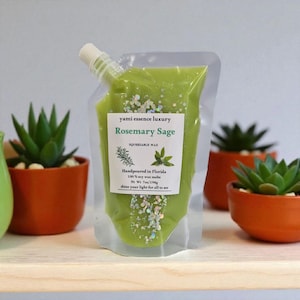 Może przedstawiać: Przezroczysta torebka wypełniona zielonymi woskami zapachowymi, oznaczona jako "Rosemary Sage". Torebka ma białą nasadkę i etykietę z tekstem i ilustracjami botanicznymi. Tło obejmuje małe sukulenty w doniczkach.