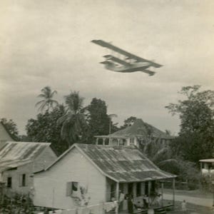 HERMOSA postal antigua de RPPC con foto real - "Sobre tierras del sur" - Avión en movimiento sobre casas, fotografía vernácula