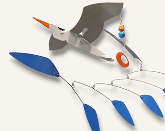 May include: A modern metal mobile featuring a stylized bird in flight, with a silver body, orange beak, and blue wing accents. The mobile includes blue leaf-shaped elements and orange and blue spherical accents.