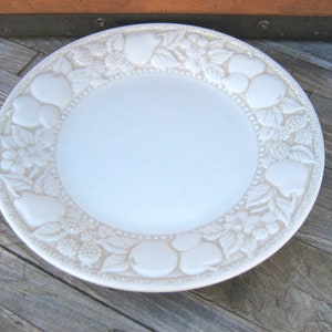 May include: White ceramic plate with a raised design of fruit and leaves around the edge.