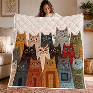 May include: A quilted throw blanket featuring a repeating diamond stitch pattern and a colourful embroidered design of numerous cats in various shades of orange, black, grey, red, and green, each with unique facial expressions and decorative patterns.