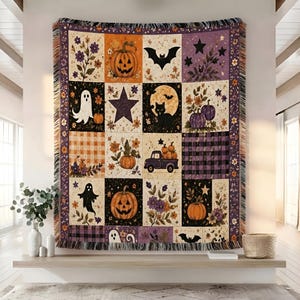 May include: A woven throw blanket featuring a grid of Halloween-themed squares. Designs include jack-o'-lanterns, ghosts, a black cat, a bat, a truck carrying pumpkins, stars, and floral patterns in shades of orange, purple, black, and cream.