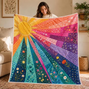 May include: A rectangular quilt featuring a vibrant sunburst design with radiating rays in a spectrum of colours including yellow, orange, pink, purple, and blue. The fabric panels are decorated with various floral patterns and stitched details.