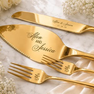 May include: A gold-toned cake serving set consisting of a serrated cake knife, a cake server, and two forks. The knife is engraved with "Afon & Jessica 11.10.25", the server with "Afon AND Jessica", and the forks with "Mr" and "Mrs" respectively.