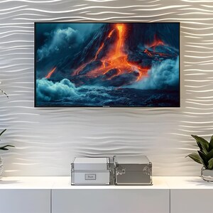 Puede incluir: Un televisor de pantalla plana grande muestra un paisaje volcánico con lava naranja y nubes oscuras. El televisor está montado en una pared blanca texturizada. Debajo, dos cajas de almacenamiento plateadas se asientan sobre un mueble blanco.