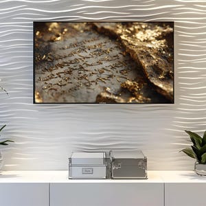 May include: A television screen shows a close-up of an ancient manuscript with gold detailing. The TV is mounted on a white, textured wall. Beneath, two silver storage boxes are on a white cabinet, with a plant to the right.