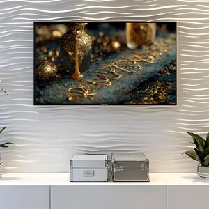 May include: A television screen shows a close-up of a gold liquid pouring from a decorative bottle. The word "LOVE" is spelled out in gold lettering. The TV is mounted on a white, textured wall above two silver storage boxes.