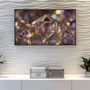 May include: A television screen displays a close-up of a geometric crystal structure with gold accents and purple gemstones. Below the screen, two silver boxes sit on a white surface, with a plant in a silver pot to the right.