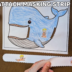 May include: A blue whale coloring page with a small figure inside, and the text "4. ATTACH MASKING STRIP" at the top. A person is holding a white strip with a drawing of a small figure.